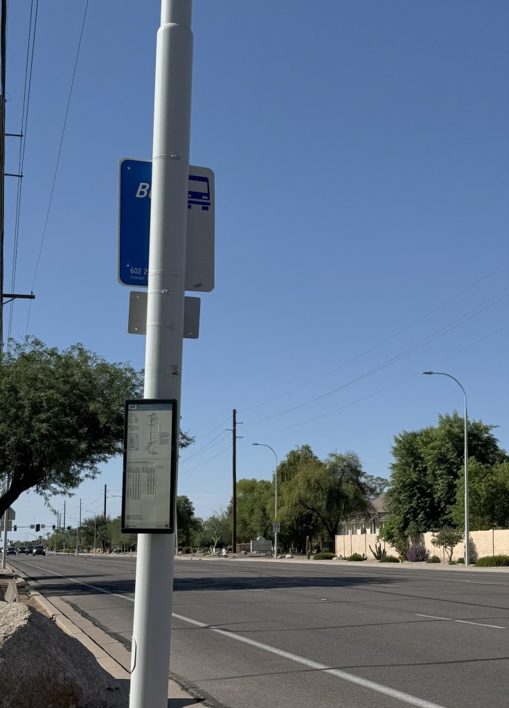 A bus stop along a wide suburban street. 