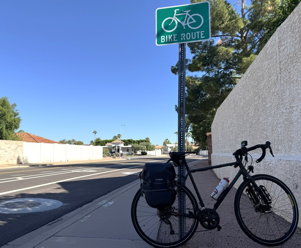 A bicycle leans against a bicycle route sign