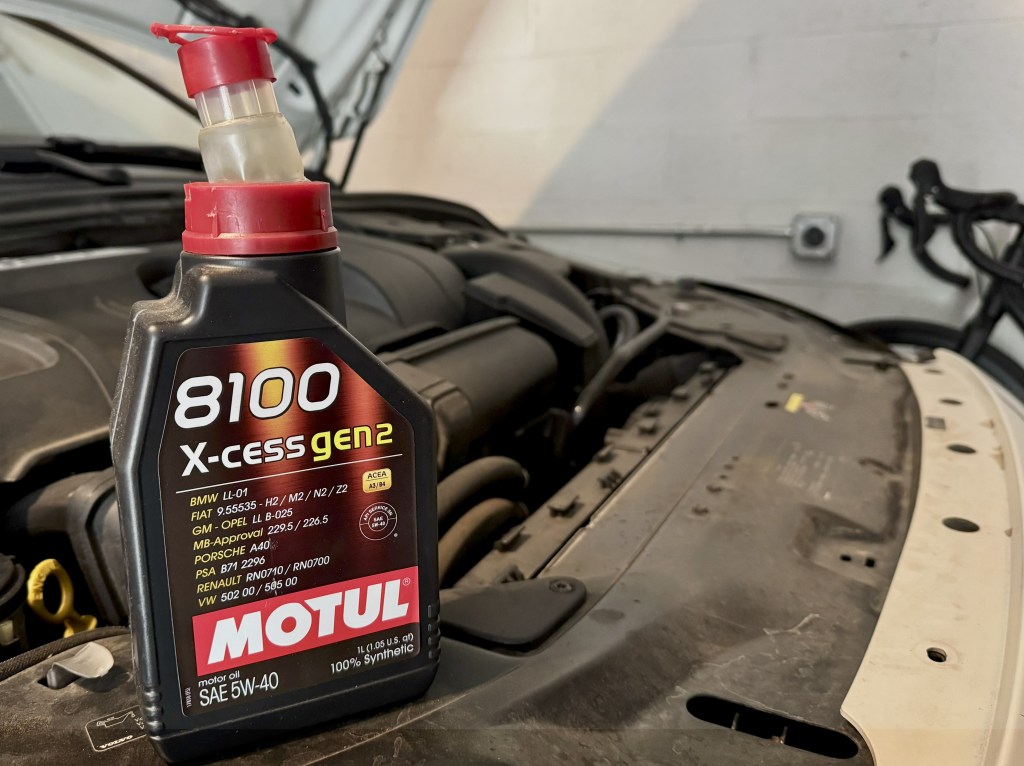 An oil jug sits on top of an engine bay.