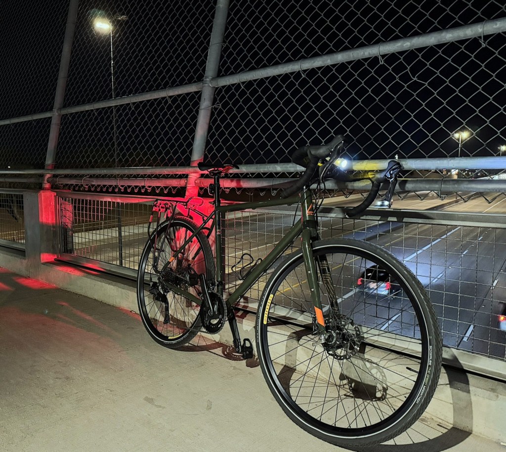 A bicycle leaning against a fence on a bridge.