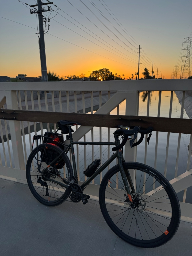 A gravel bike sits on a bridge at sunrise