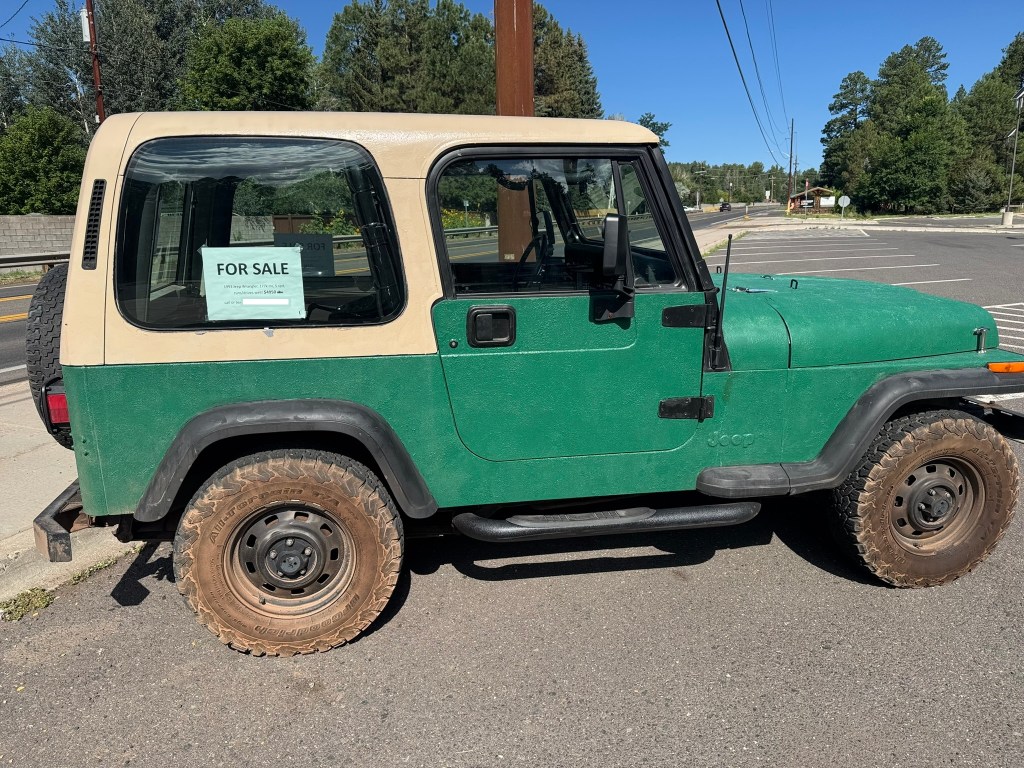 An old Jeep Wrangler for sale in a parking lot